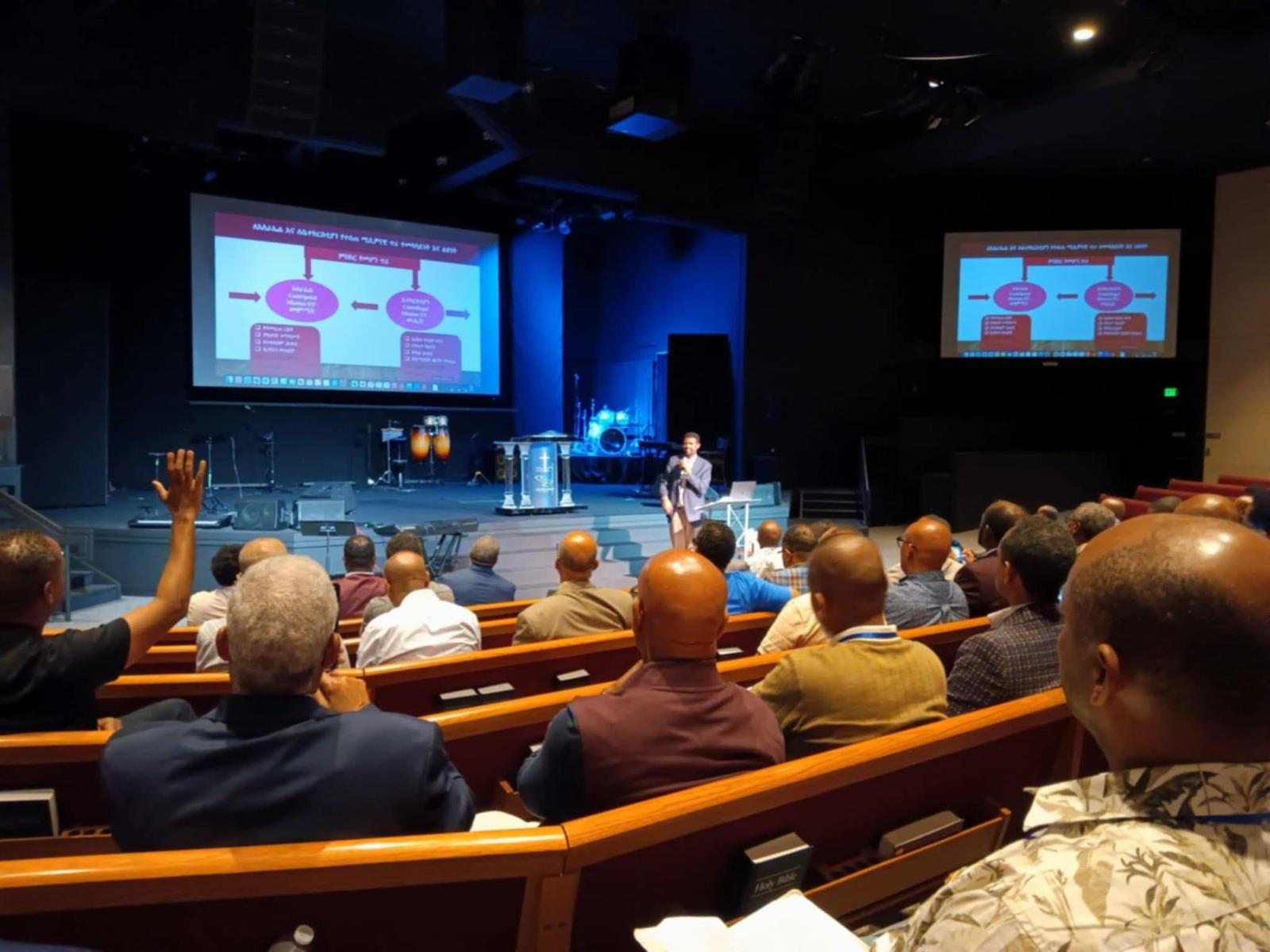 Participants in an auditorium viewing a mission presentation.