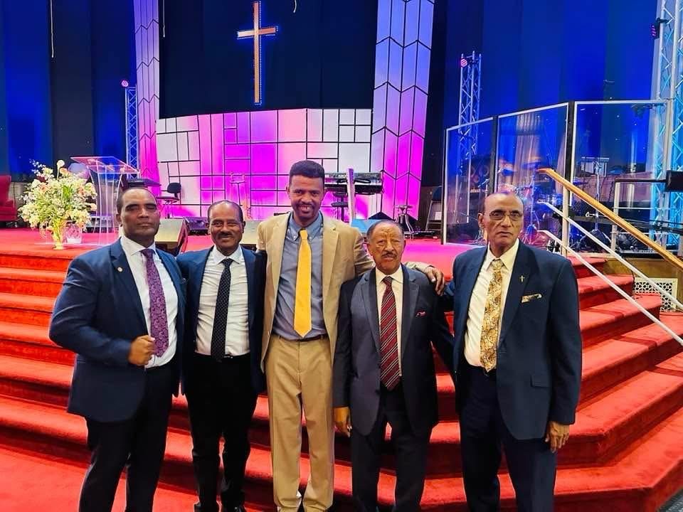A group of ministry participants standing together near a church stage.