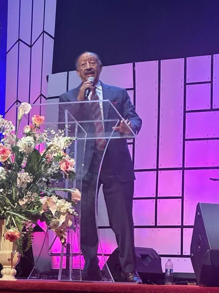 A speaker at a lectern on a church stage.