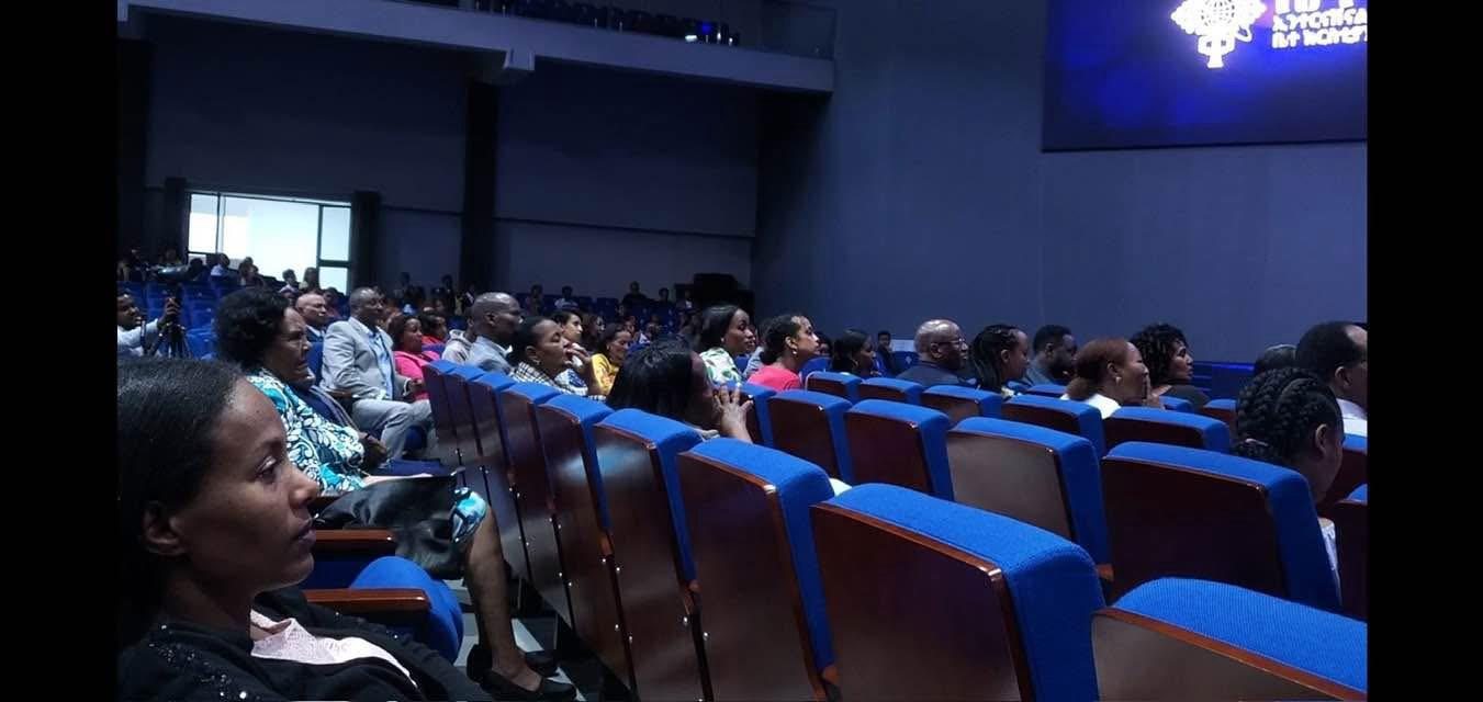 Participants seated in rows inside an auditorium.